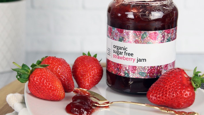 Glitter label applied to strawberry jam jar on a white plate