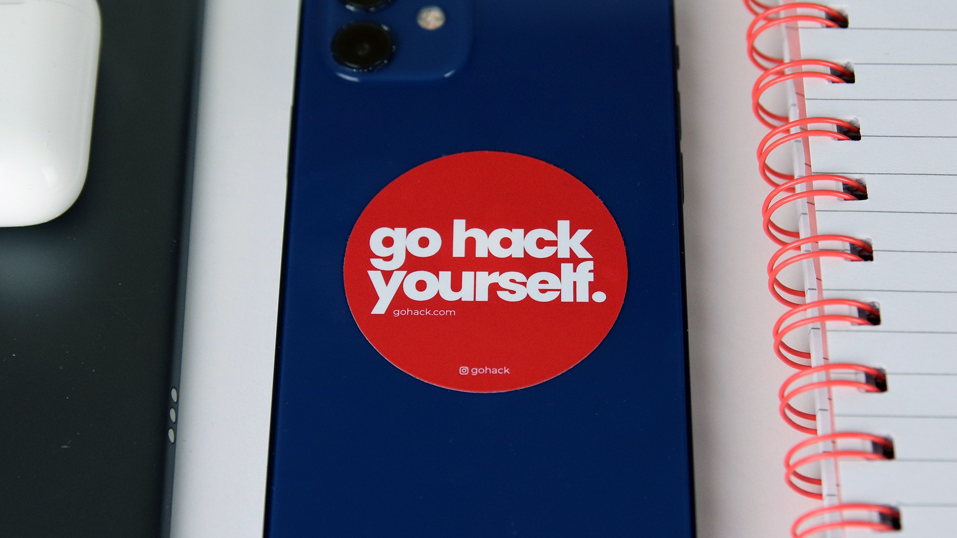 Round white vinyl sticker with go hack yourself design applied to a blue iPhone