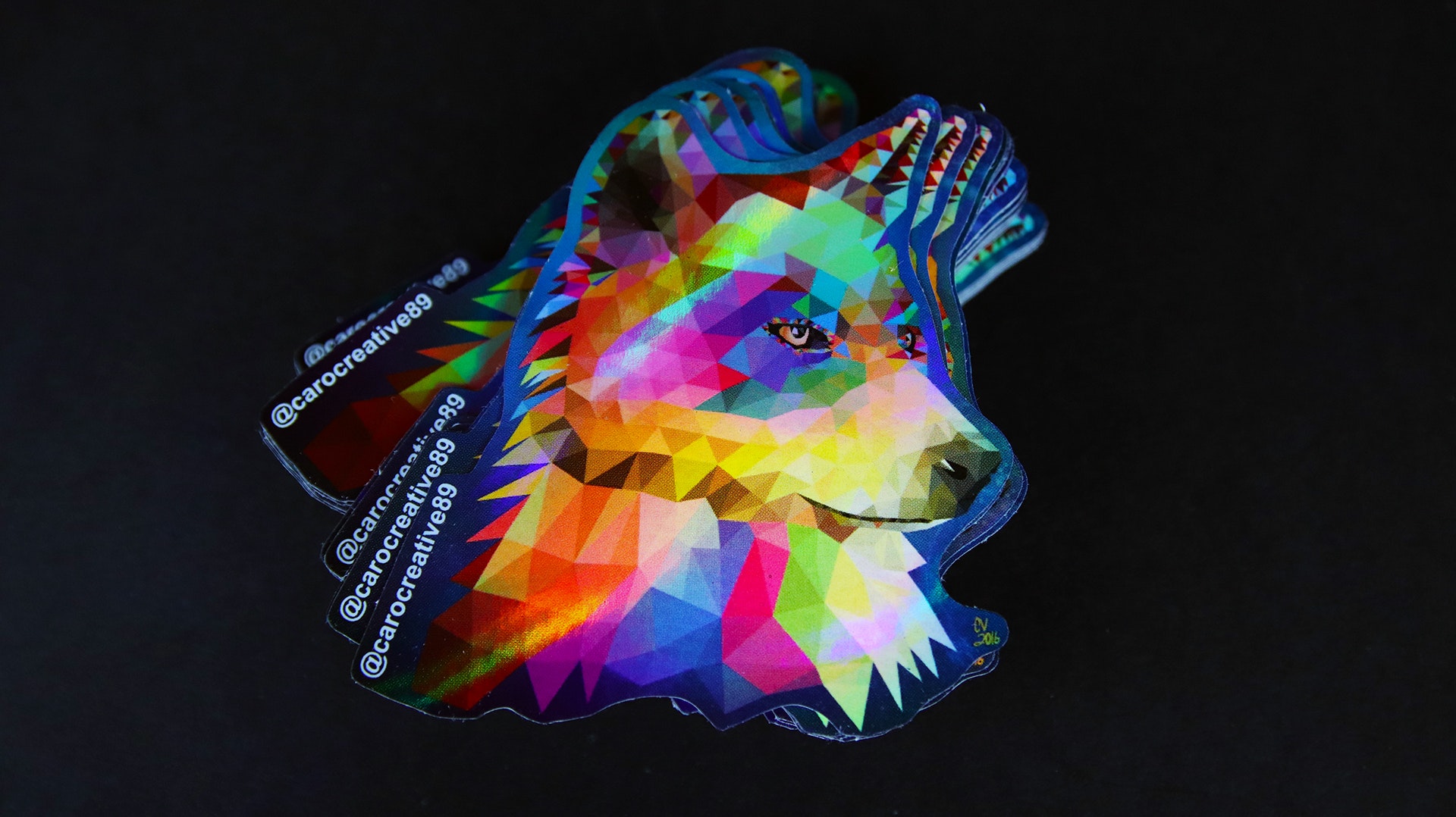 Die cut holographic sticker with geometric wold design against a black background