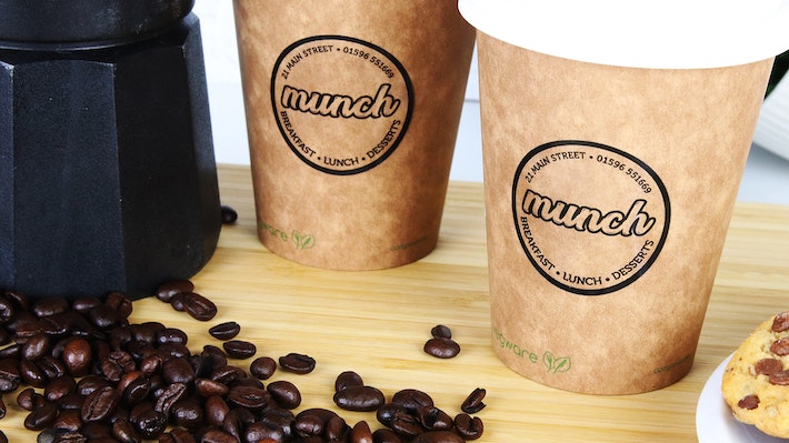 Round clear eco friendly stickers with munch design applied to brown paper coffee cups