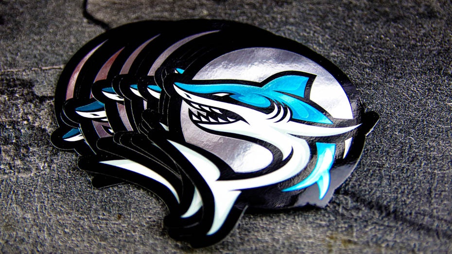 Stack of die cut mirror silver sticker with shark design on a table