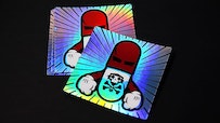 Stack of square holographic stickers with pillman design