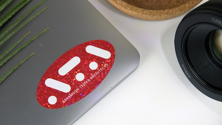 Oval glitter sticker with red ATA logo applied to a silver laptop