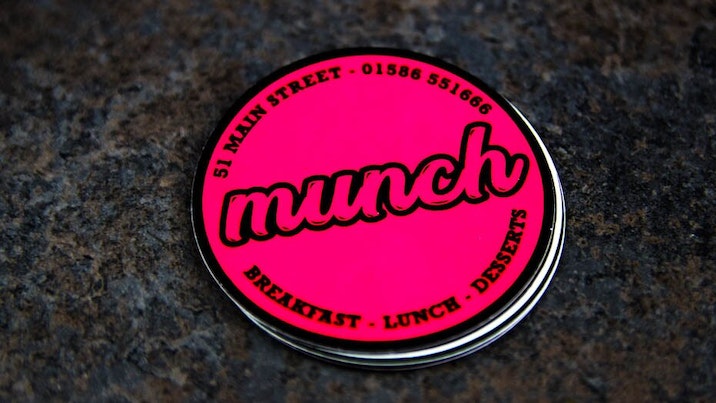 Circle fluorescent pink stickers with munch design on a table
