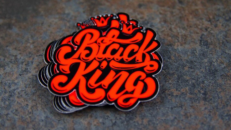 Stack of die cut fluorescent red stickers with black king design on a table
