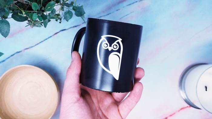 White transfer sticker with owl design applied to a black mug
