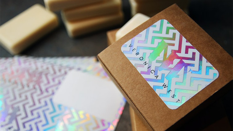 Holographic sheet labels with rounded corners applied to a cardboard soap box