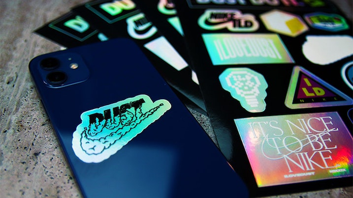 Die cut holographic sheet labels with one design peeled and applied to a black phone
