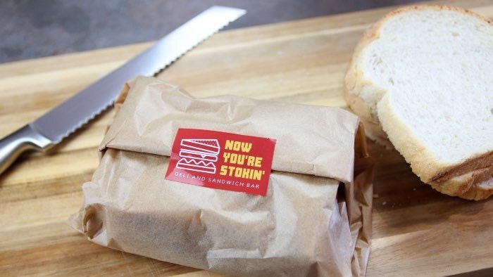 Rectangular eco-friendly sticker with sandwich logo applied to seal a food packaging