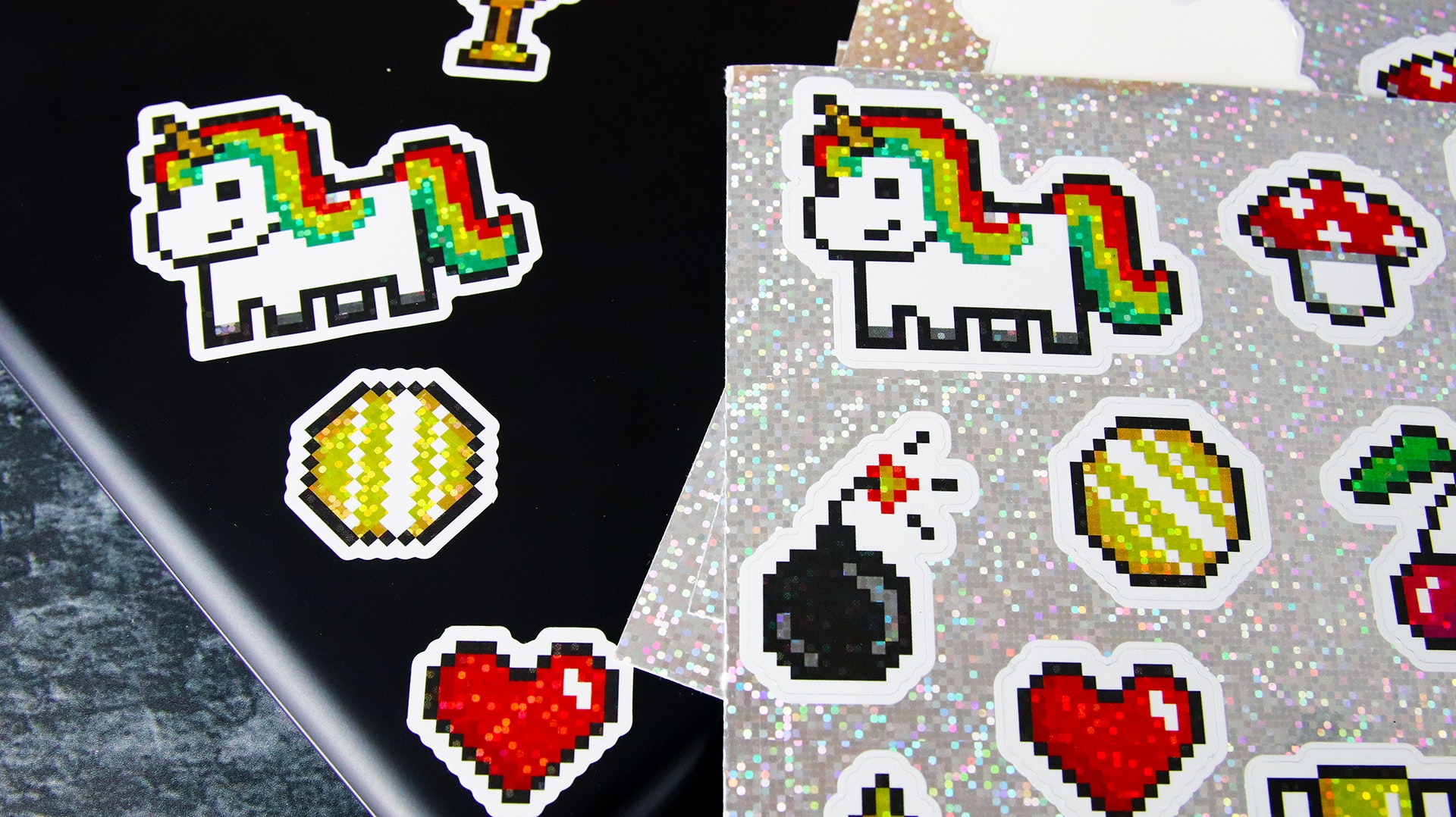 Sticker sheet with glitter labels with different cute designs applied to a black laptop