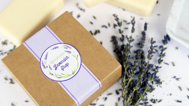 Die cut biodegradable paper stickers applied to a cardboard box filled with lavender soap