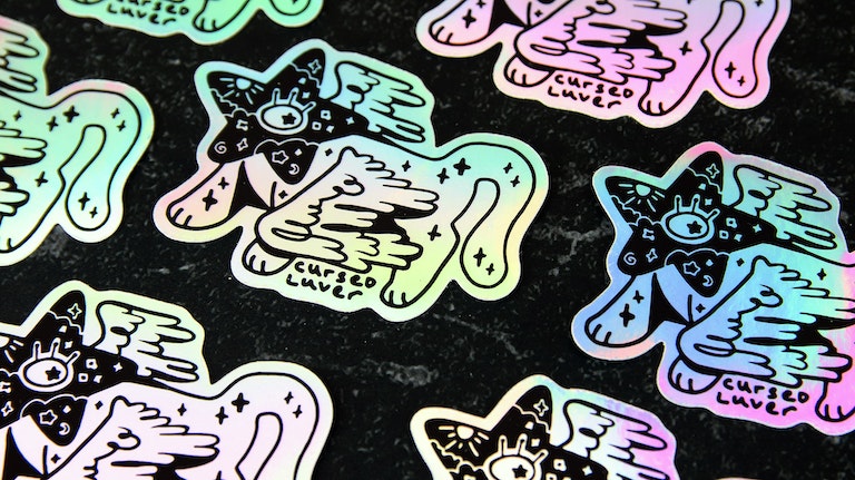 Die cut holographic stickers with cat art design on a black table