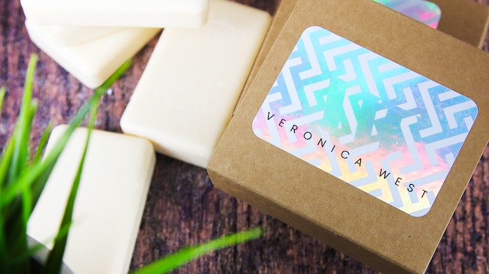 Rounded corner holographic sticker with victoria west logo applied to cardboard soap boxes