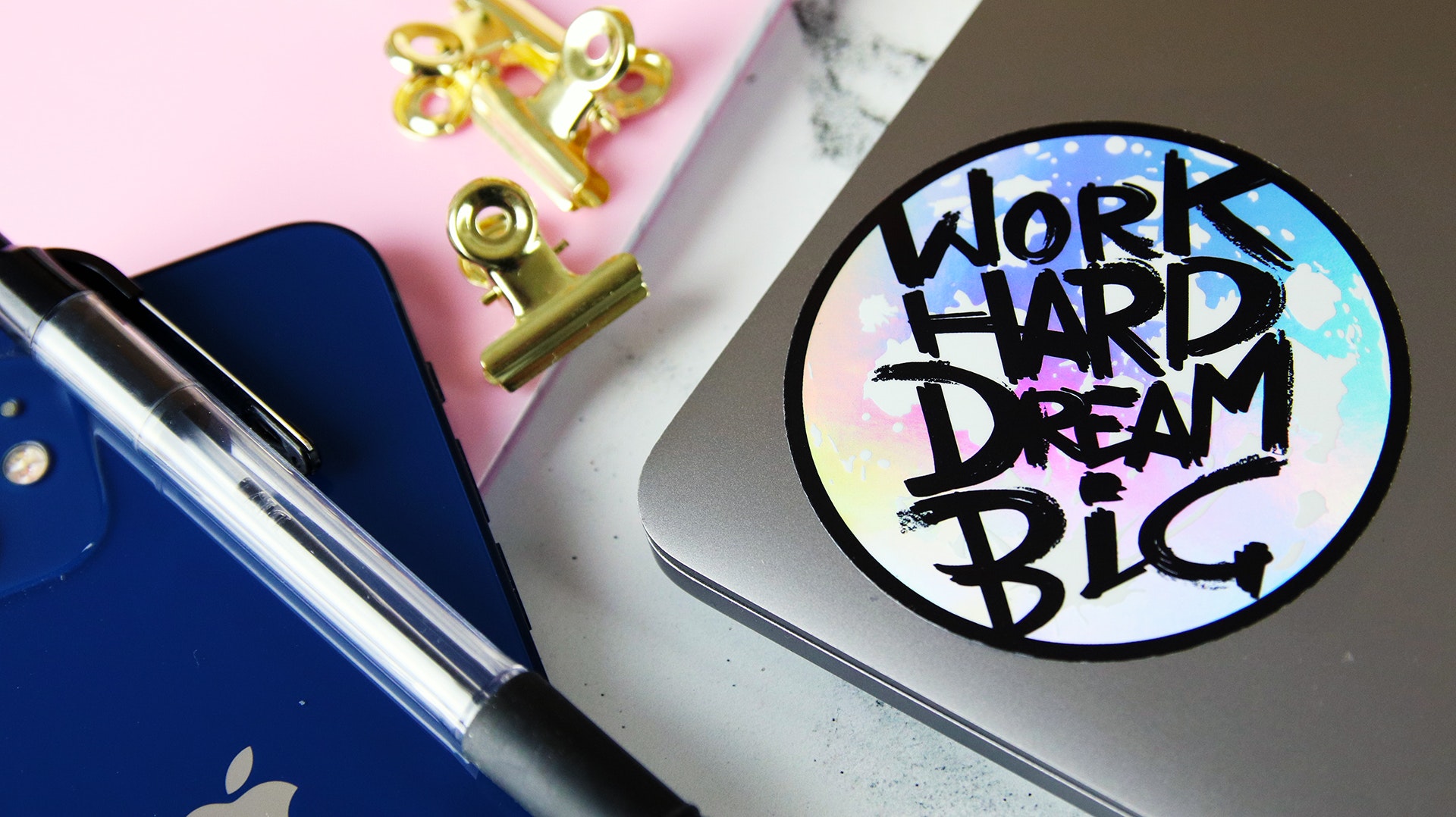 Circle holographic sticker with work hard dream big design applied to a silver laptop
