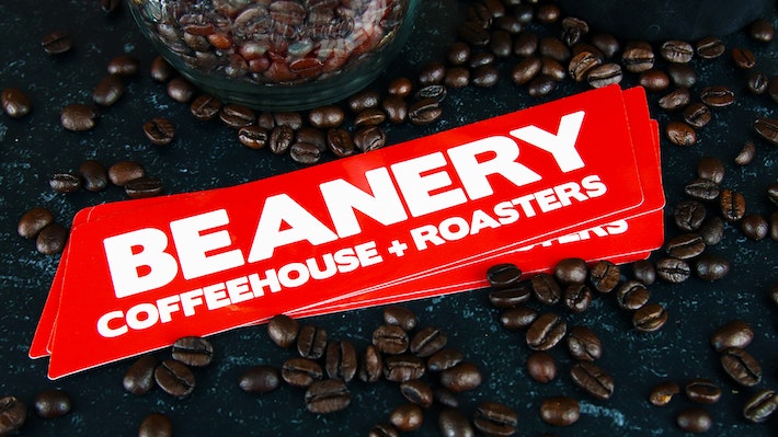 Die cut eco-friendly logo sticker amidst coffee beans