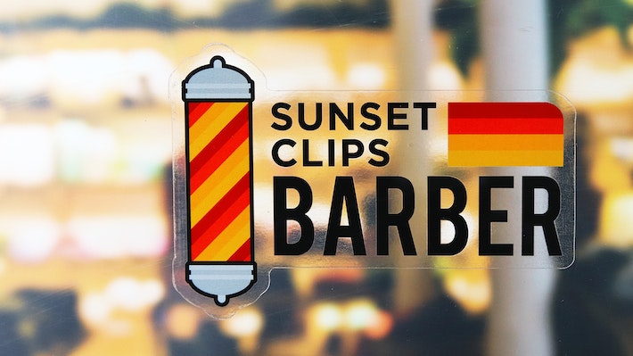 Eco-friendly front adhesive die cut sticker with sunset clips barber logo applied to a window