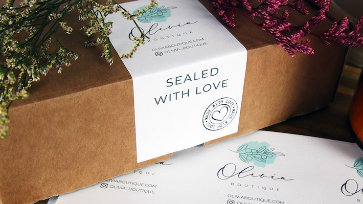Biodegradable paper sheet labels with logo and sealed with love design used as a packaging seal on a cardboard box