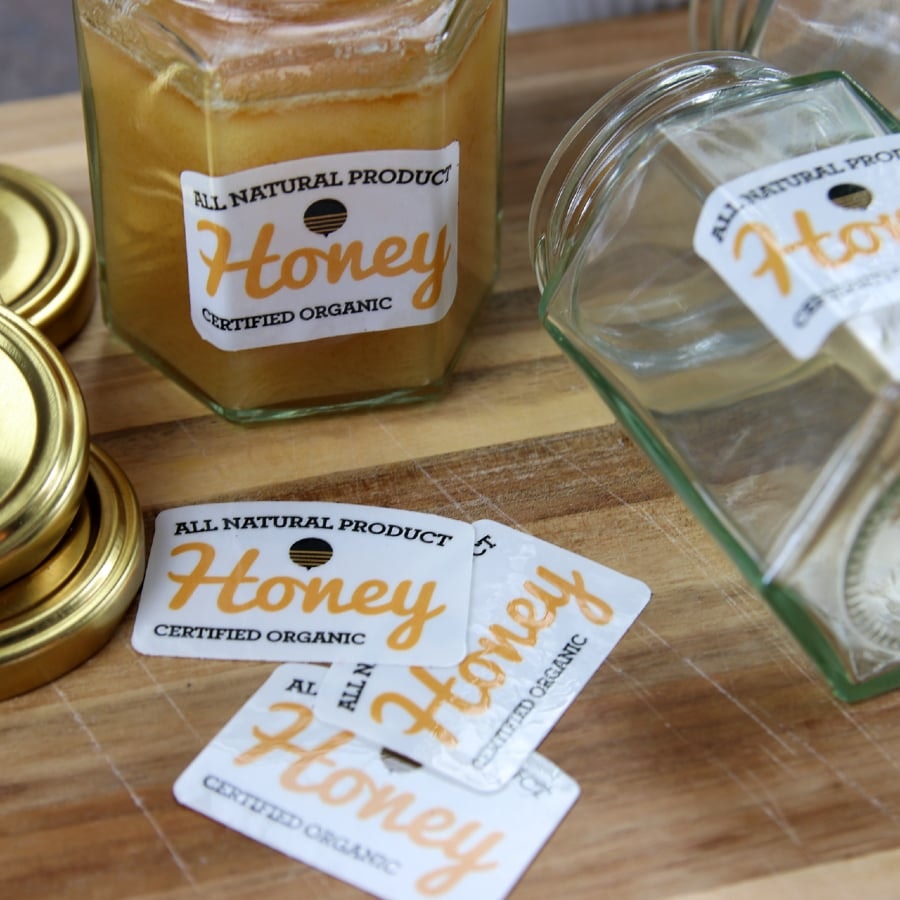 Eco-friendly stickers applied to honey jars on a wooden block