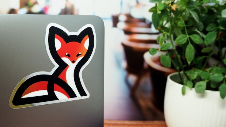 Mirror silver die cut sticker with fox logo applied to the back of a silver laptop