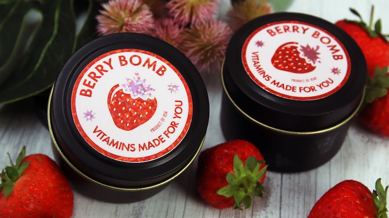 Circle glitter labels applied to black tins containing a custom made vitamin mix