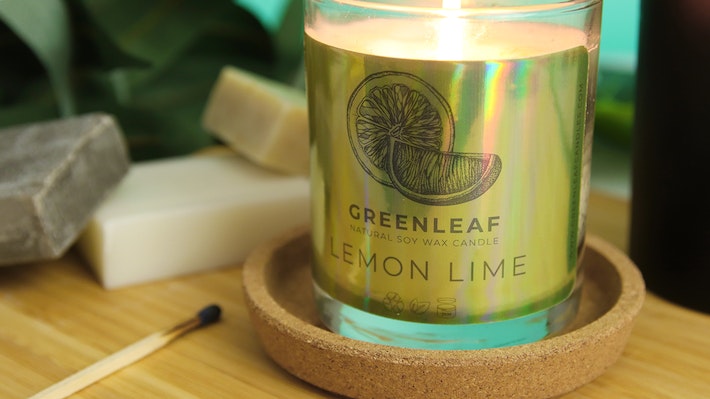 Eco-friendly holographic sticker with green leaf label applied to a candle