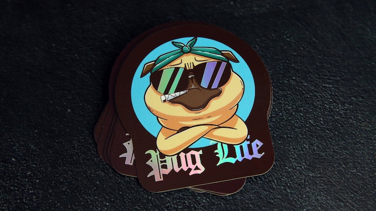 Stack of eco-friendly holographic die cut stickers with pug life design